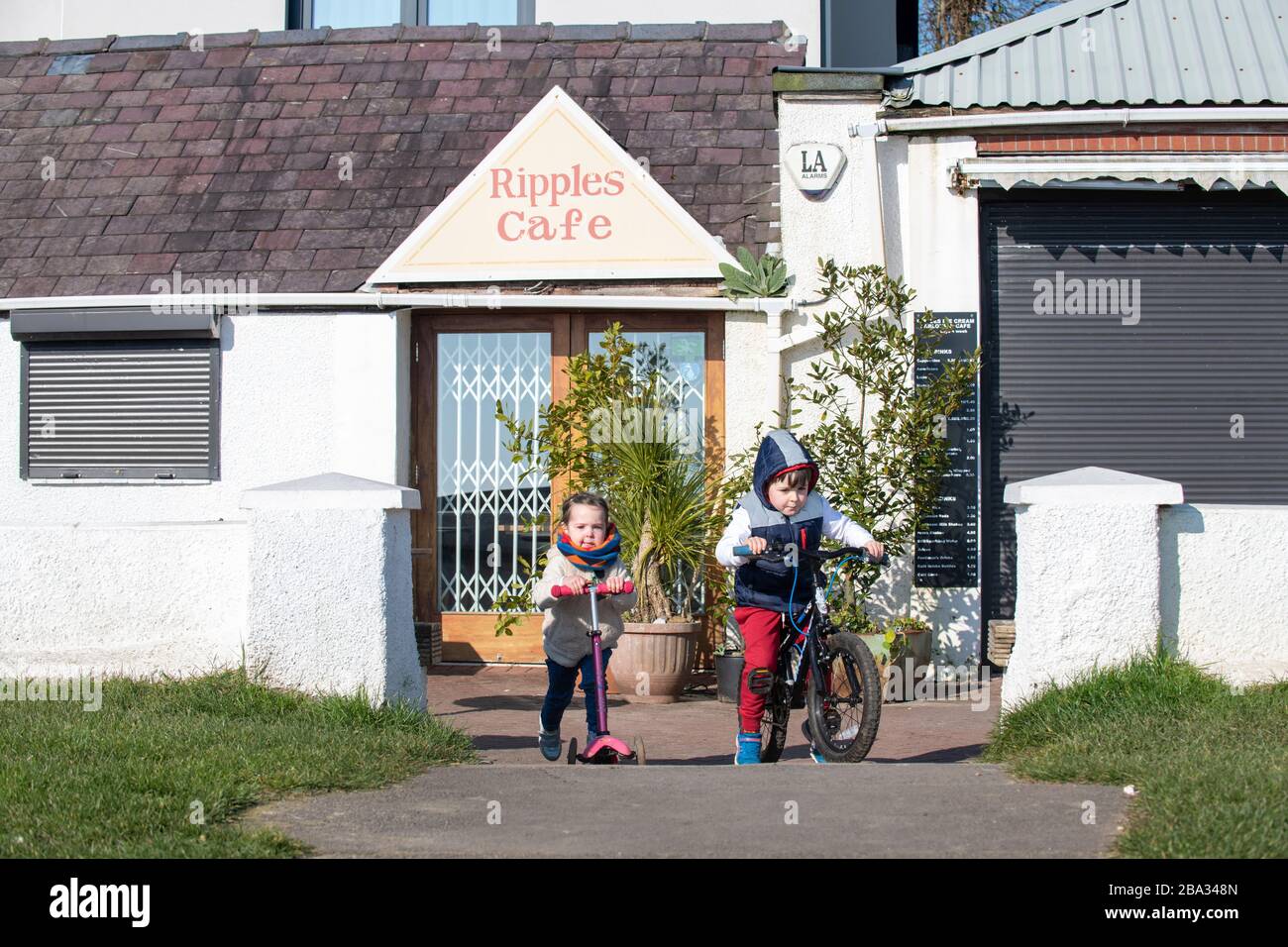 Young girl and boy outside a cafe which is closed due to the Government lockdown due to coronavirus/Covid-19 pandemic; people are not allowed out.asid Stock Photo