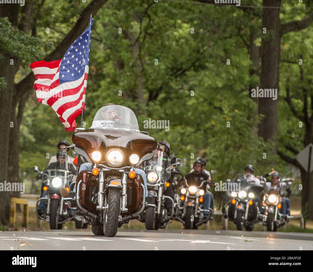 Rolling Thunder rally event with multiple motorcycles and a big American flag leading the way. Stock Photo