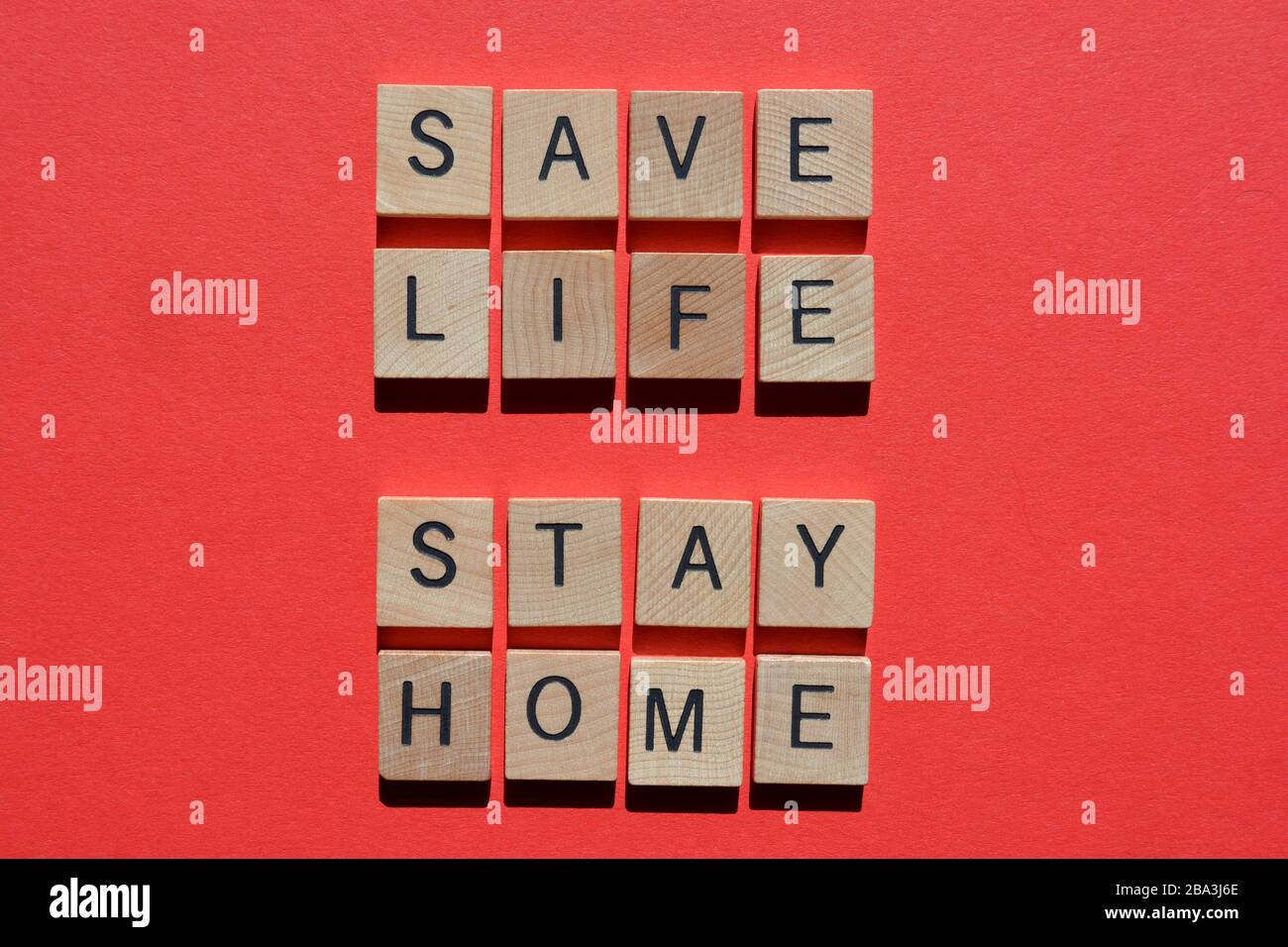 Save Life, Stay Home, words in wooden letters on red background Stock Photo