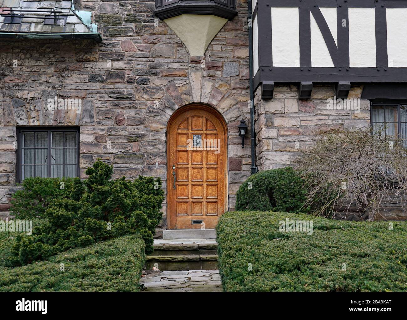 Round top wood panel front door  of Tudor style stone house Stock Photo