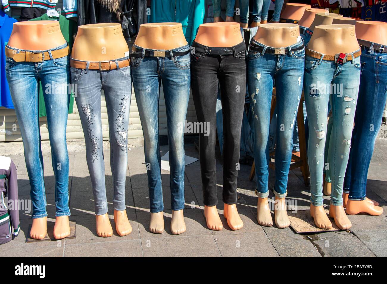 Jeans are offered for sale at the bottom of mannequins in front of a