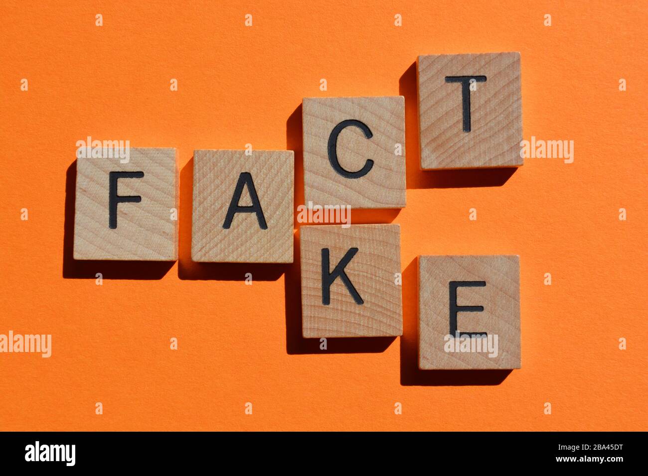Fact and Fake, words in wooden alphabet letters on orange coloured background Stock Photo