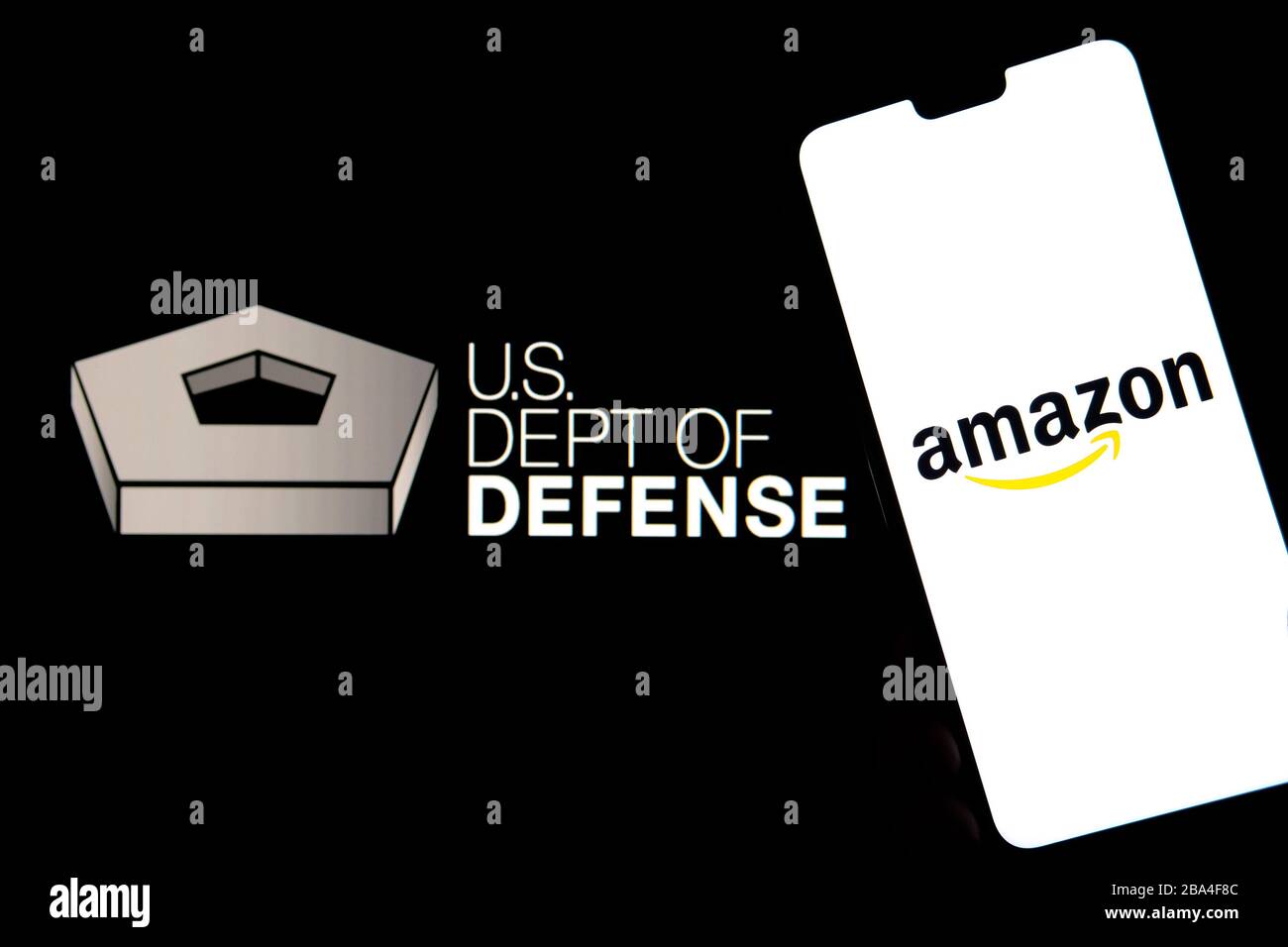 Stone / United Kingdom - March 25 2019: Amazon logo on a smartphone and US Dept of Defence on the blurred background. Stock Photo