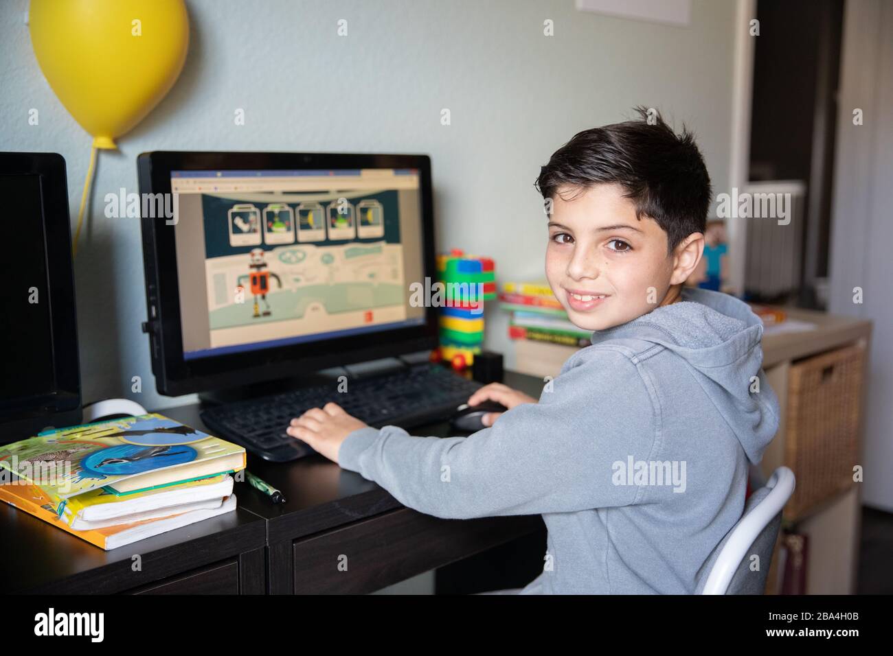 Cute young boy studying at home on computer due to school closures because of corona virus outbreak in the world. Stock Photo