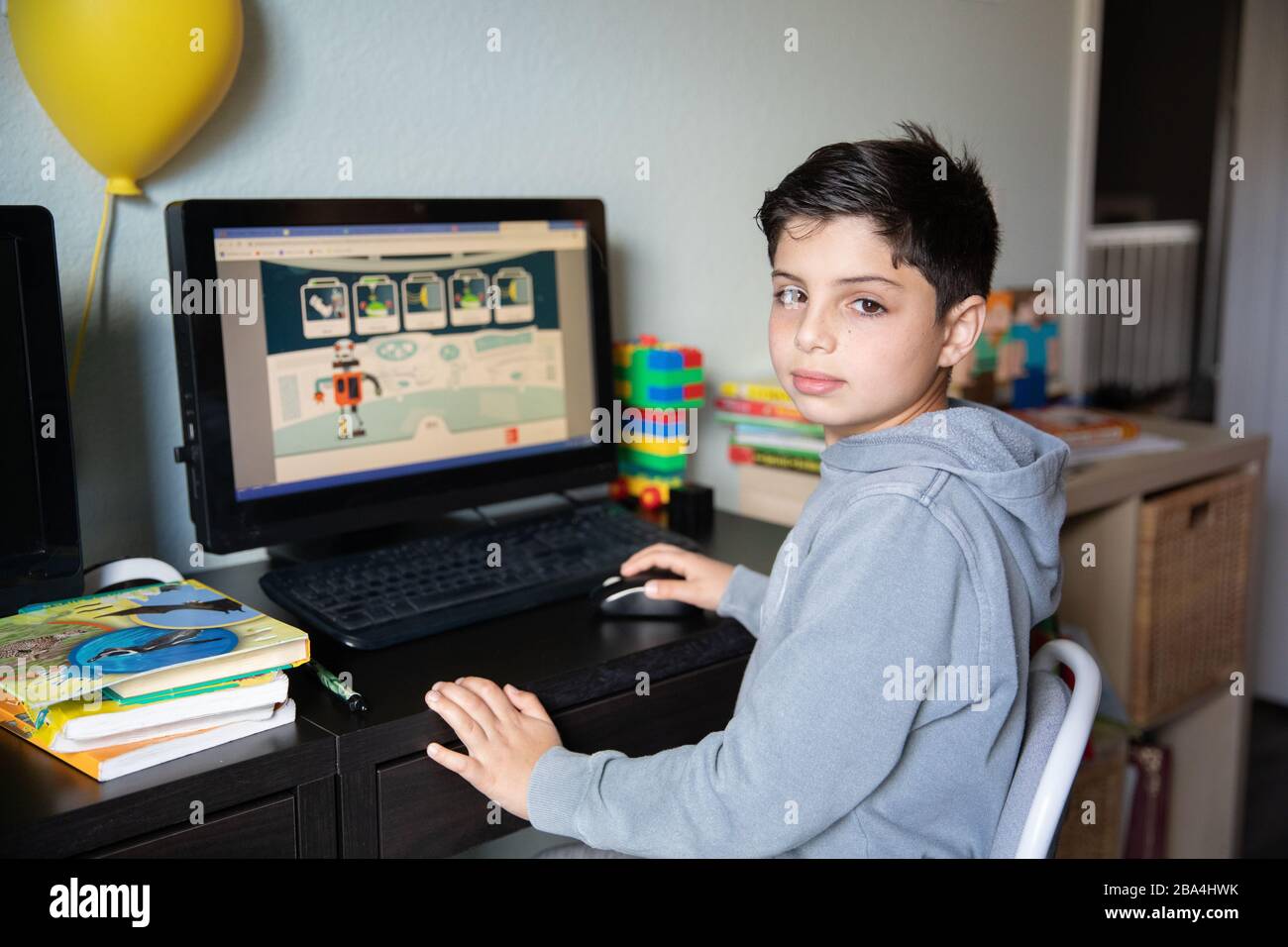 Cute young boy studying at home on computer due to school closures because of corona virus outbreak in the world. Stock Photo