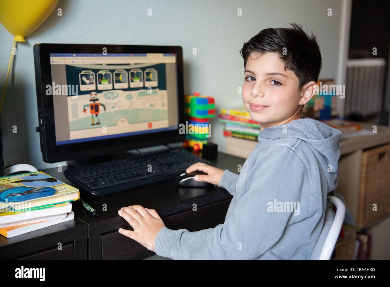 Cute young boy studying at home on computer due to school closures because of corona virus outbreak in the world. Stock Photo