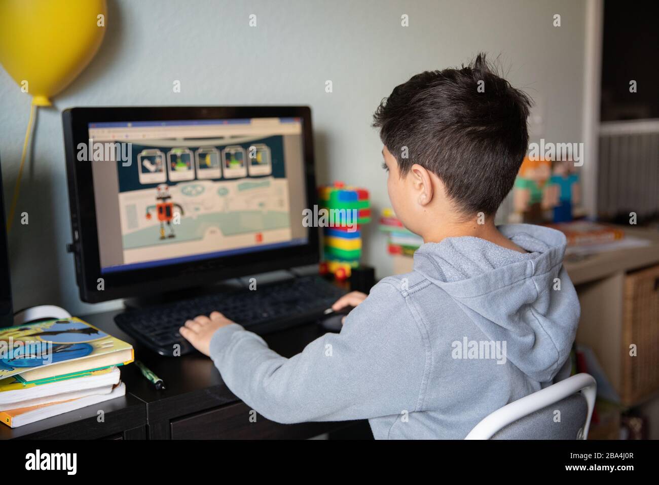 Cute young boy studying at home on computer due to school closures because of corona virus outbreak in the world. Stock Photo