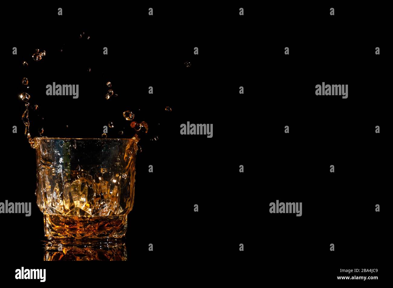 Whisky drinks with ice cubes making a splash Stock Photo