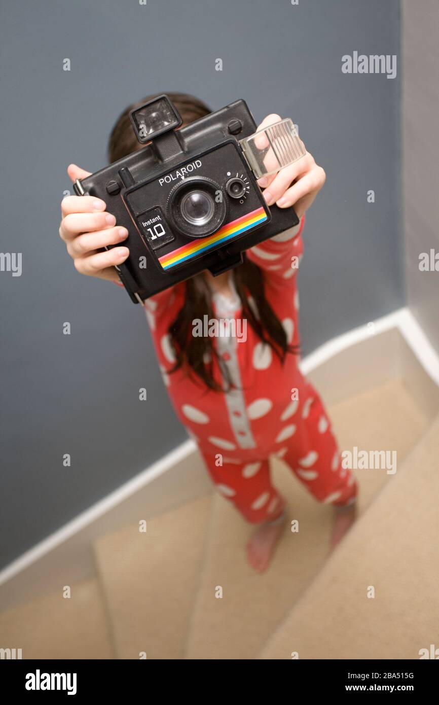 Young girl taking a picture with an old polaroid camera Stock Photo