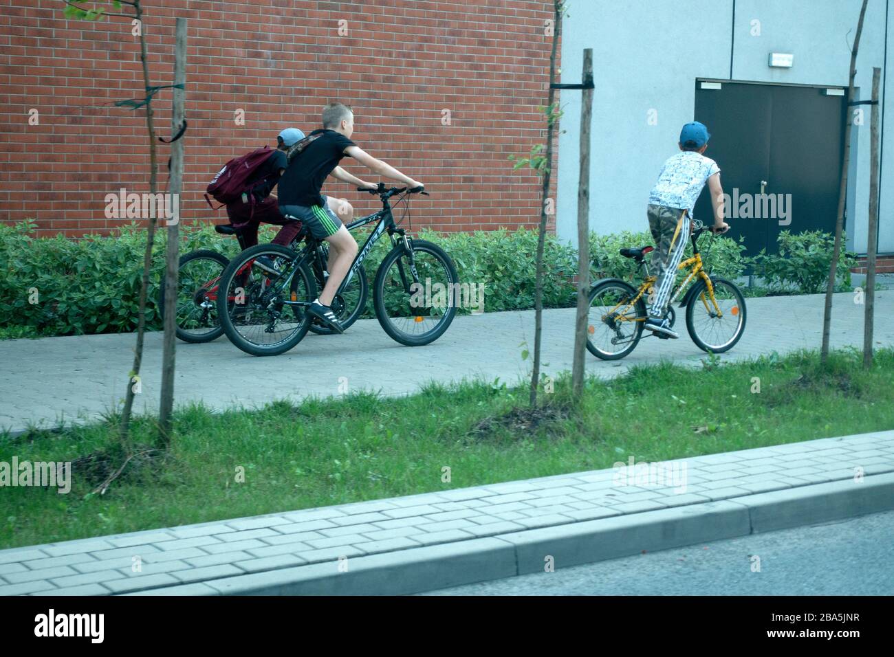 Three boys bicycling on the sidewalk. Tomaszow Mazowiecki Central Poland Stock Photo