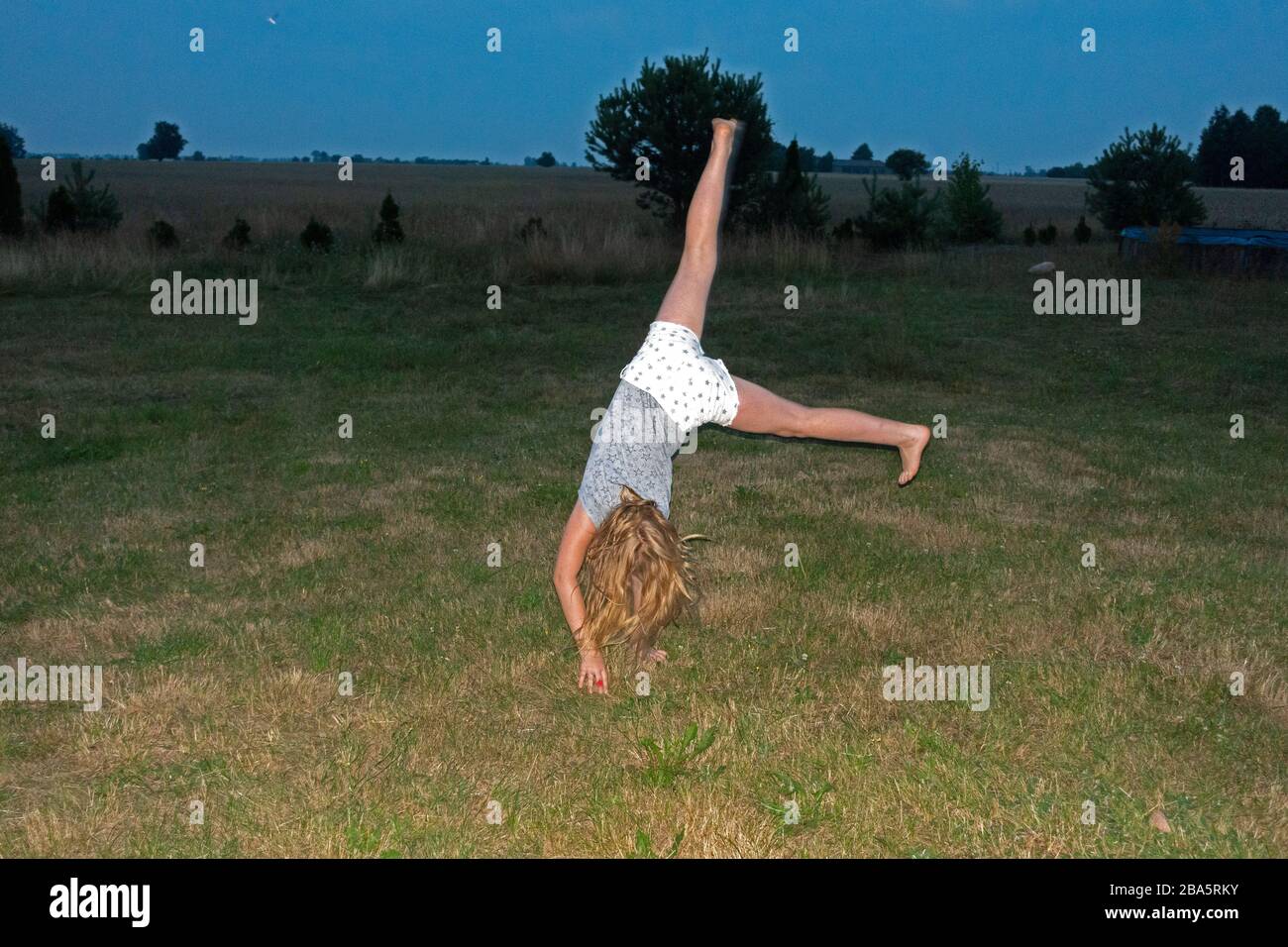 Athletic preteen girl  doing a cartwheel in her front yard. Zawady Gmina Rzeczyca Poland Stock Photo