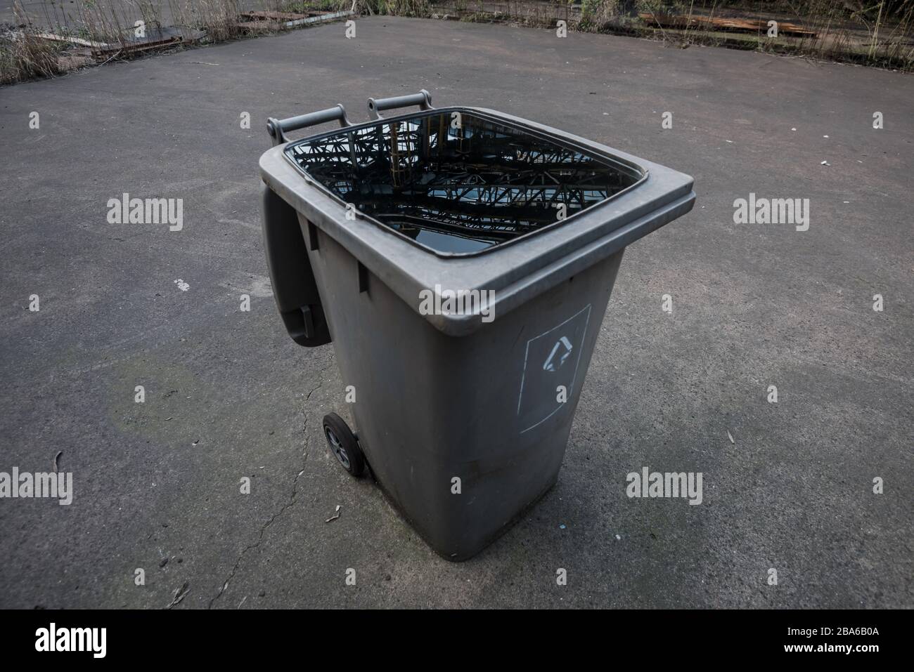 an abandoned garbage bin full of rainwater in an abandoned factory Stock Photo