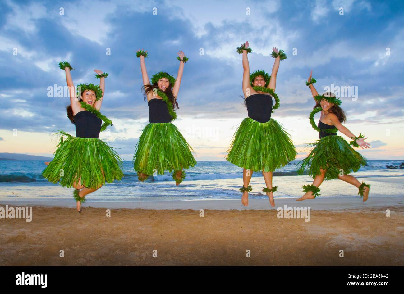 Four hula dancers jump for joy at Palauea, Maui. Hawaii. Stock Photo