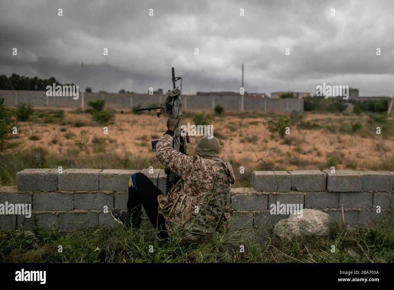 Tripoli, Libya. 25th Mar, 2020. A UN-backed Government of National Accord (GNA) fighter loses balance during clashes with East-based Libyan National Army (LNA) at Ain-Zara frontline in Tripoli, Libya, March 25, 2020. The Minister of Health of Libya's UN-backed government, Ehmid Bin Omar, on Tuesday announced the first novel coronavirus infection in the country. Credit: Amru Salahuddien/Xinhua/Alamy Live News Stock Photo