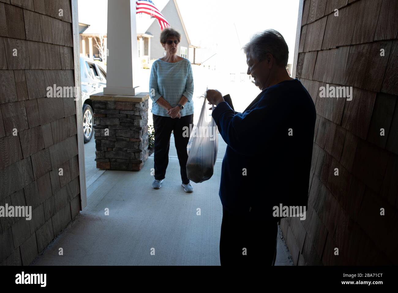 Canton, GA, USA. 25th Mar, 2020. Judy Winter, 73, and her sister-in-law Liz Winter, keep a safe distance as Liz delivers groceries. Judy, who has medical complications, requires constant oxygen and is cautious about venturing outside her home during coronavirus pandemic. 'If I got the virus, I wouldnÃt survive it, ' she said. Credit: Robin Rayne/ZUMA Wire/Alamy Live News Stock Photo