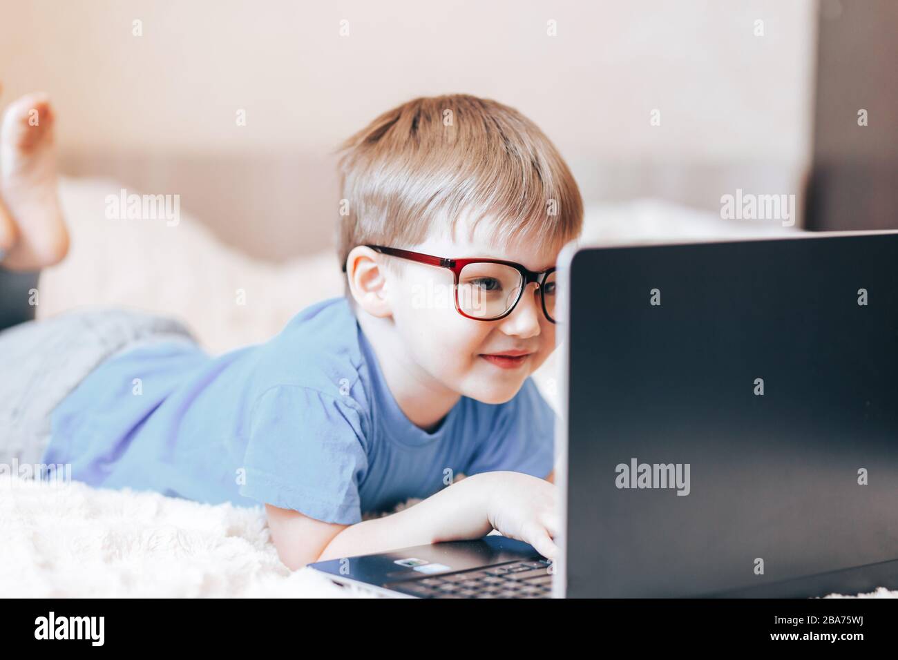 Little happy blonde boy using laptop Stock Photo - Alamy