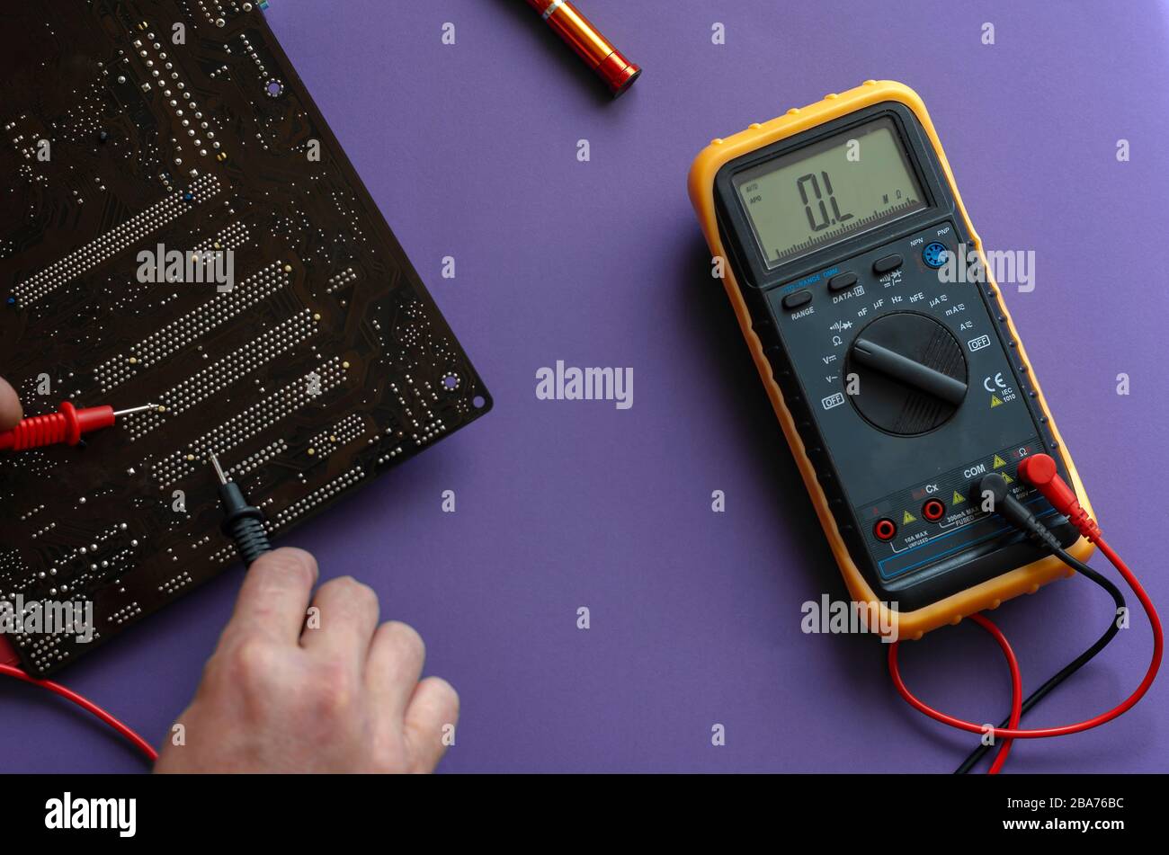 Checking the electrical resistance of the motherboard. Hands using a digital multimeter to test