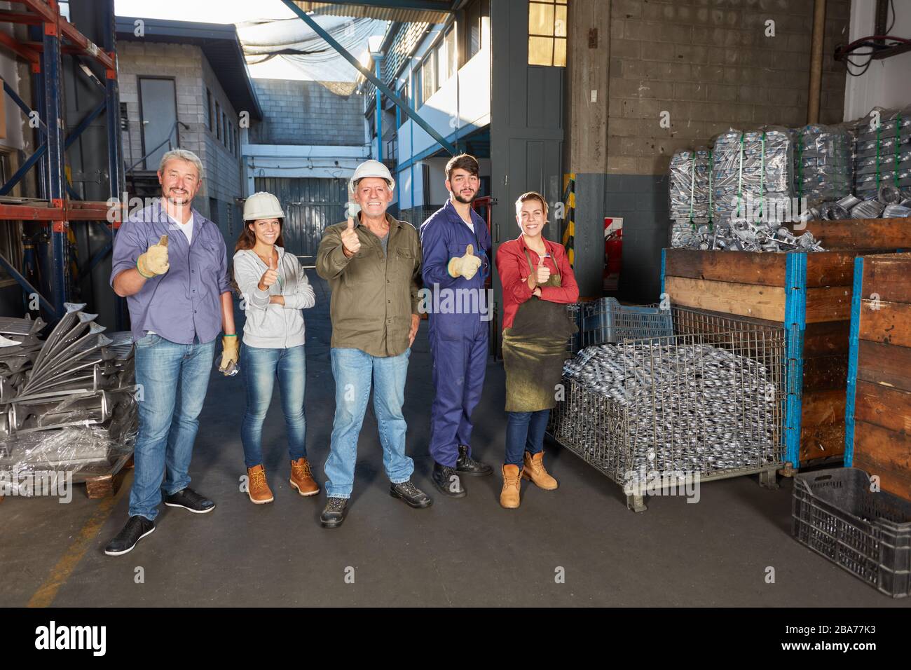 Group of workers in a metalworking factory holding their thumbs up