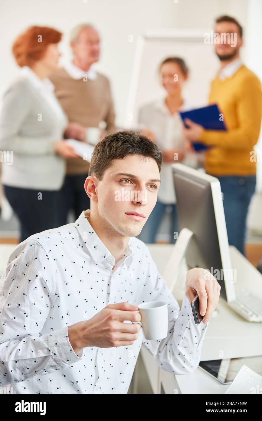 Thoughtful man sitting in front of his team having coffee in the office Stock Photo
