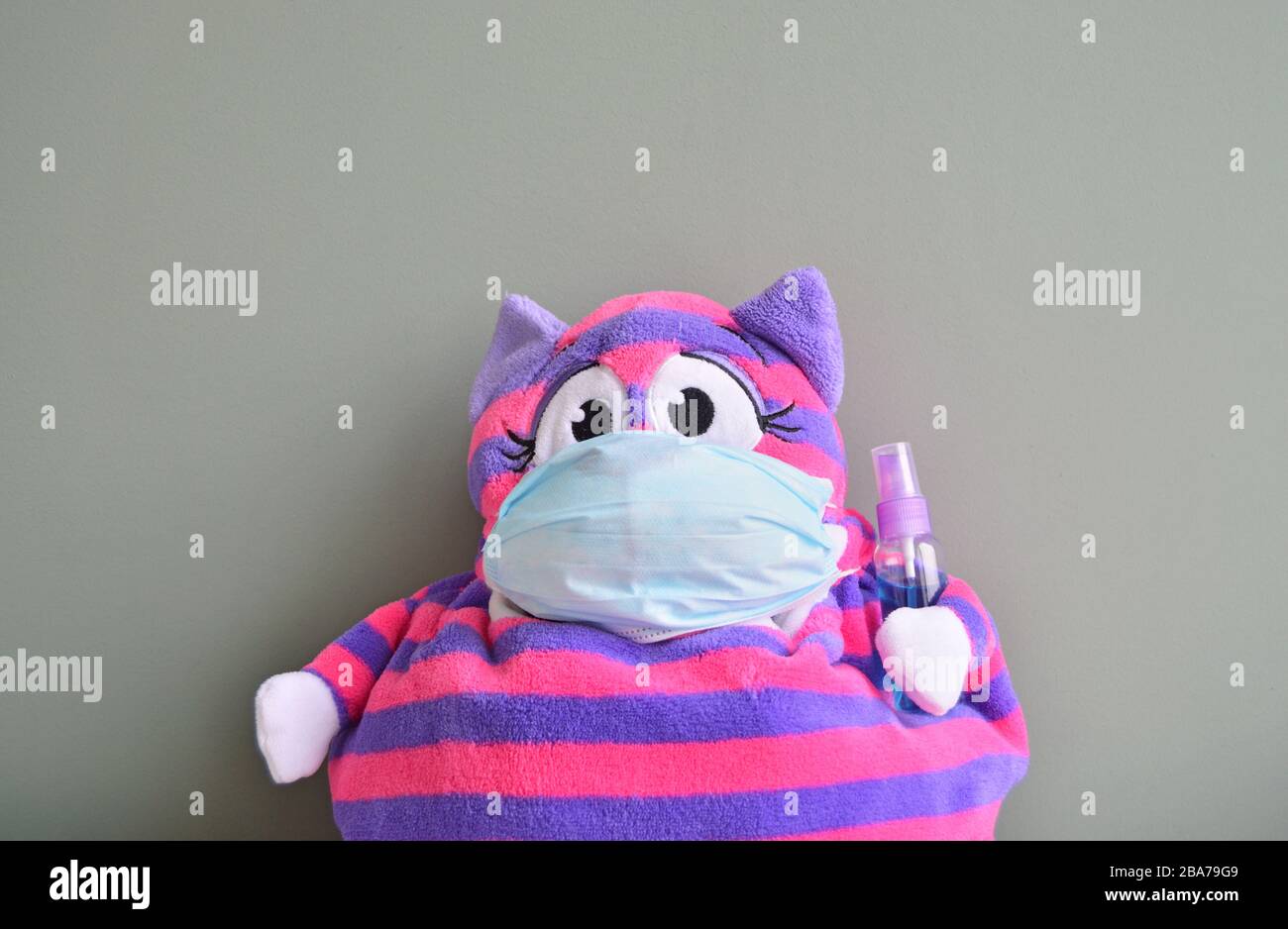 Striped stuffed toy with surgical mask and disinfectant bottle Stock Photo