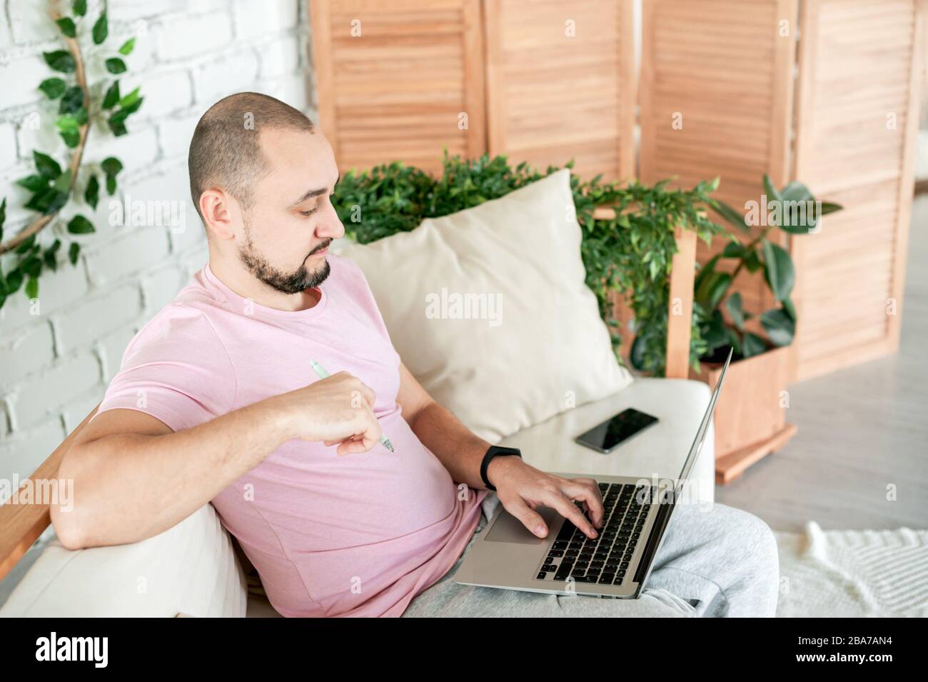 Man sitting on sofa using notebook looking on monitor Stock Photo