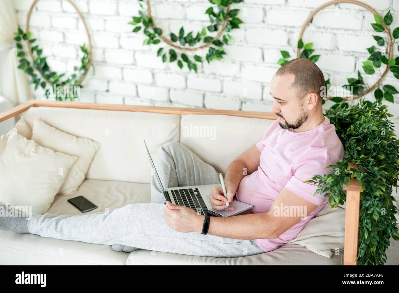 Man using laptop and taking notes at home Stock Photo