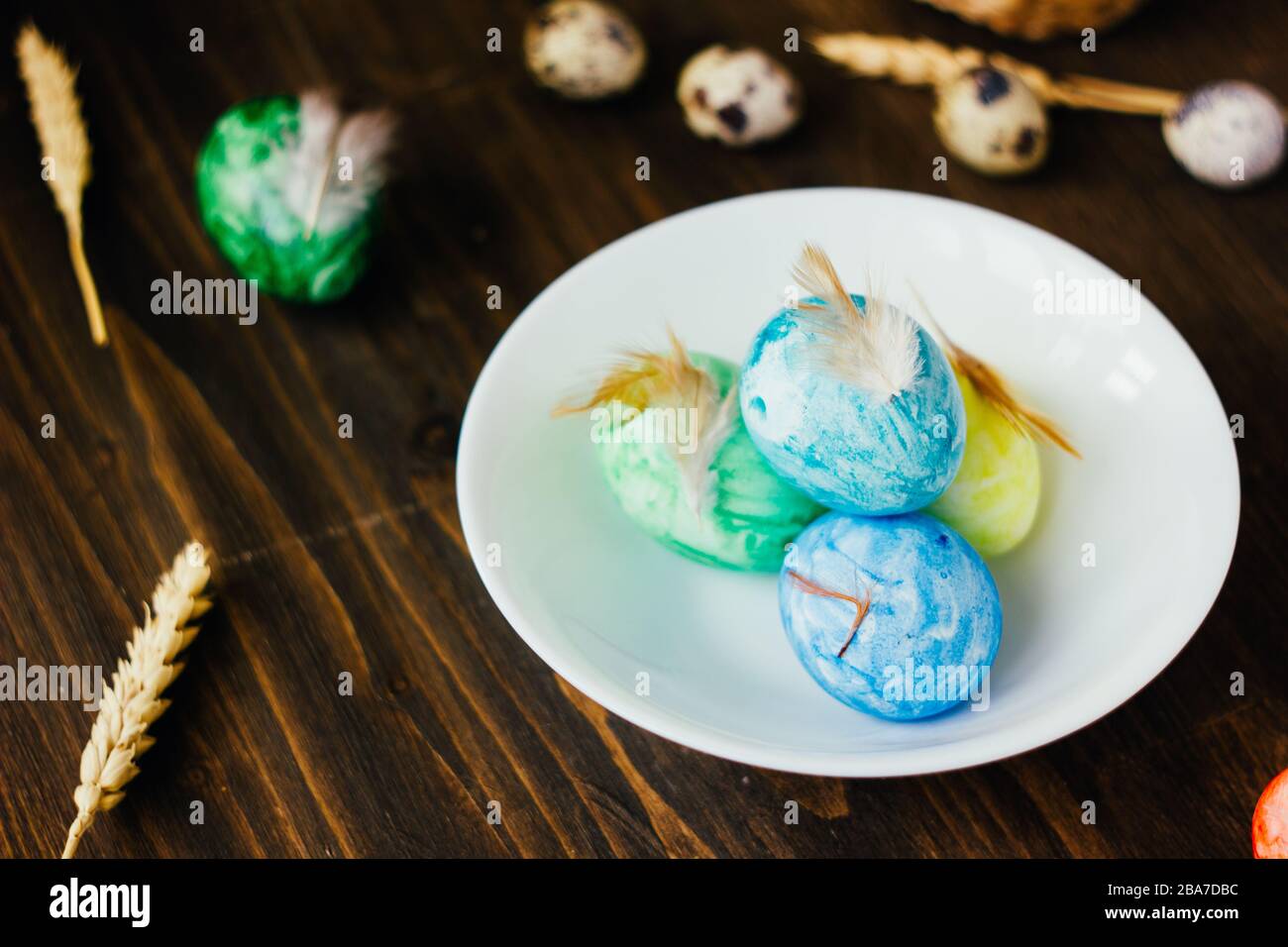 Blue, yellow and green color easter eggs on ceramic bowl over rustic table Stock Photo - Alamy