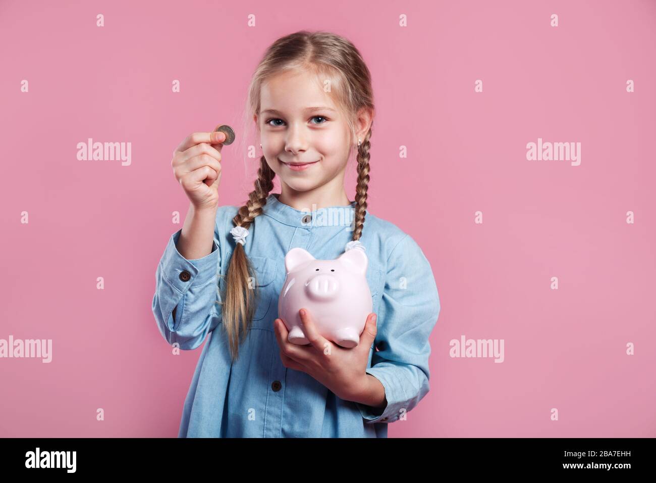 Little girl saving money in a piggybank on pink background Stock Photo ...