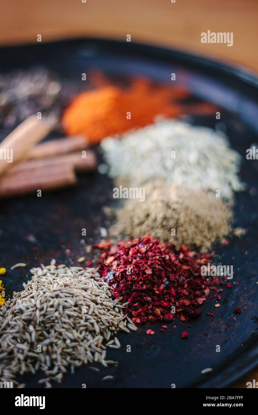 Red sumac spice on black metal plate surrounded by other spices Stock