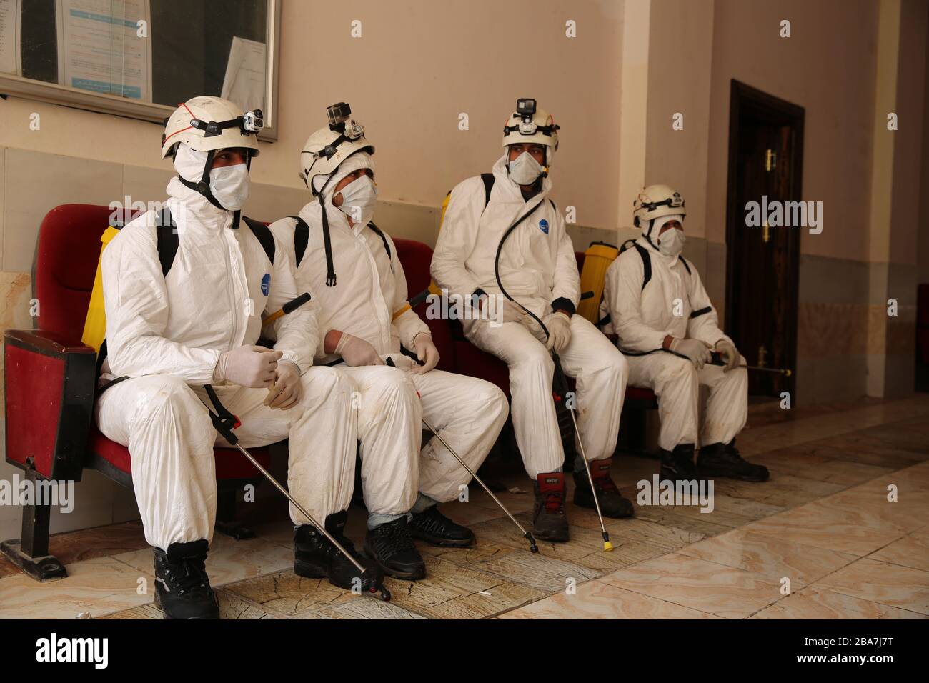 March 24, 2020: Aleppo, Syria. 24 March 2020. Members of the Syrian Civil Defence clad in protective gear spray with disinfectant the premises of a medical clinic in the town of Atarib, in the western Aleppo countryside, as part of preventive measures against the spread of the Coronavirus in the area. Although in the rebel-held northwest part of Syria no Covid-19 cases have been confirmed, some preventive measures are now in place to contain a possible epidemic in the warn-torn country. The Syrian government is also applying tight measures after the first case of Covid 19 in the country was an Stock Photo