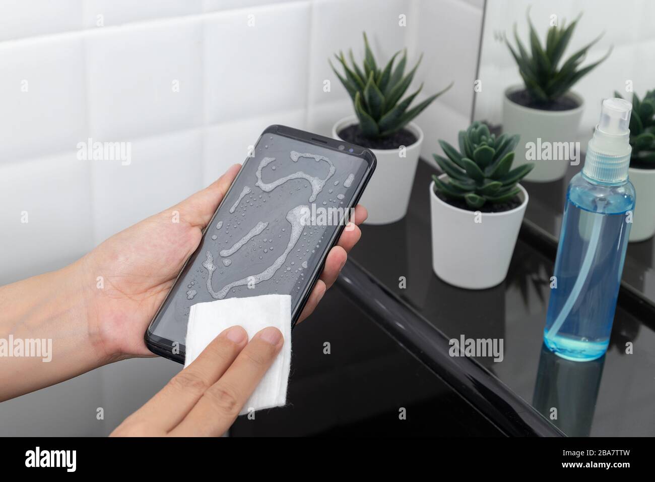 disinfect, sanitize, hygiene care. cleaning dirty stain on mobile phone touch screen for disinfection, prevention of germs spreading during infections Stock Photo