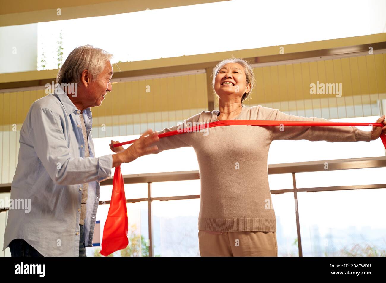 happy asian elderly couple exercising using resistance band in nursing home Stock Photo
