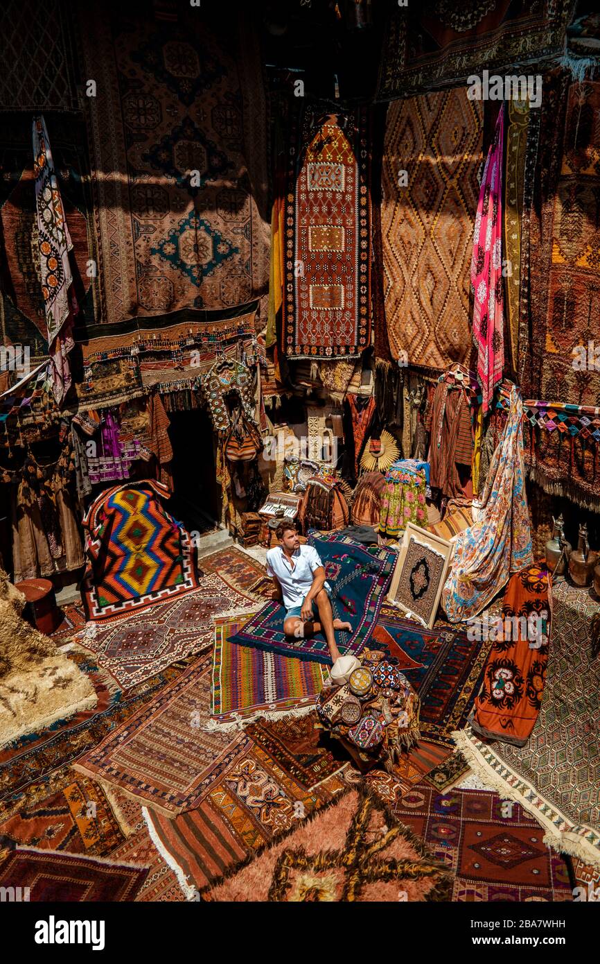 young man tourist at an old traditional Turkish carpet shop in cave house Cappadocia, Turkey Kapadokya Stock Photo