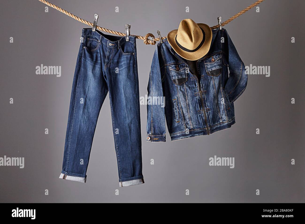 A blue jeans pants hanging from a rope next to a blue jeans jacket and cowboy hat Stock Photo