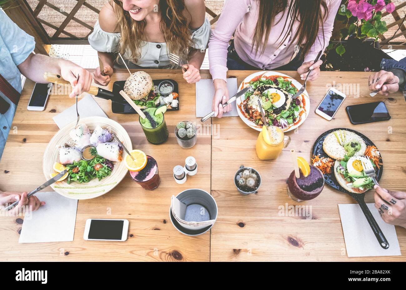 Young people eating brunch and drinking smoothie bowl at vintage bar - Happy people having a healthy lunch and chatting in trendy restaurant - Food tr Stock Photo