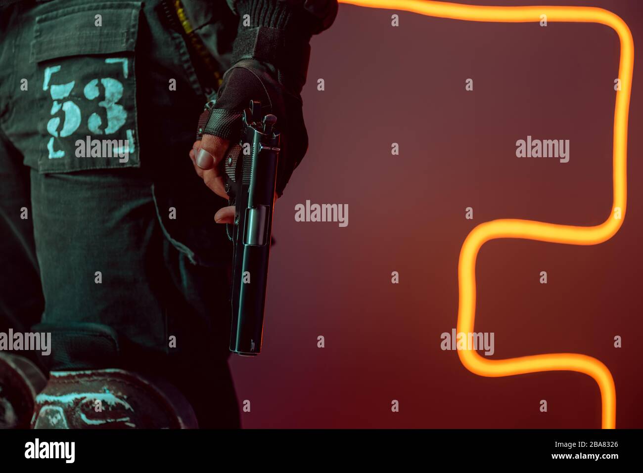 cropped view of dangerous cyberpunk player with gun on black with neon lighting Stock Photo