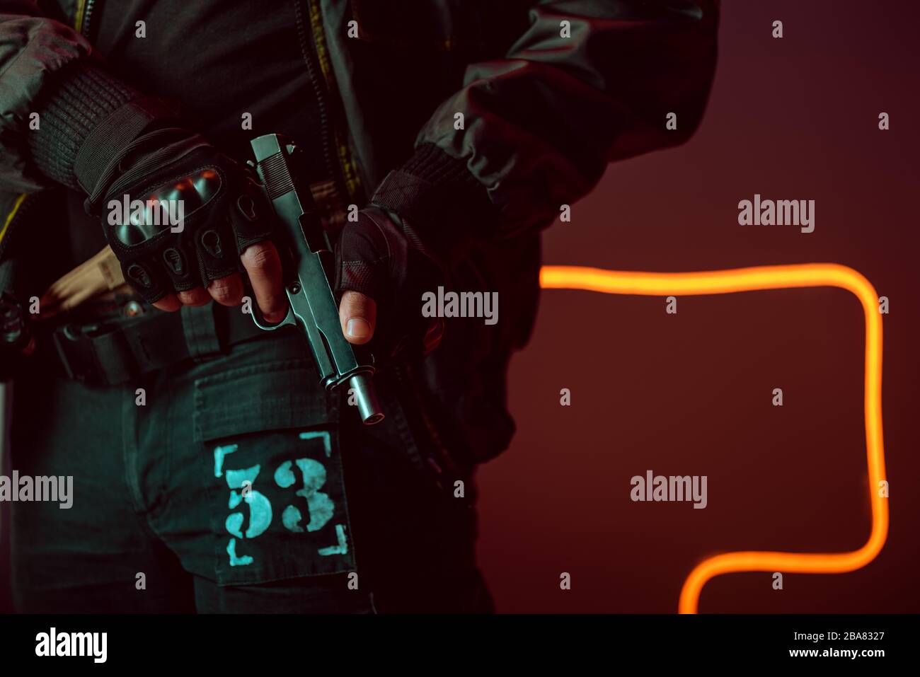 cropped view of dangerous cyberpunk player holding gun on black with neon lighting Stock Photo