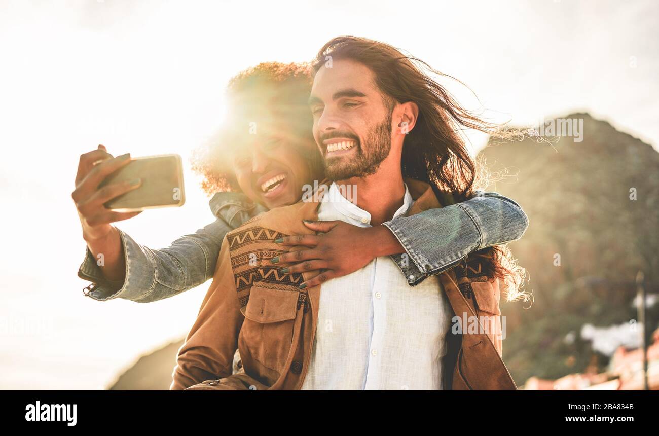 Happy couple taking selfie photo for social network story - Influencers people having fun with new trend technology - Love, lifestyle, and multiracial Stock Photo