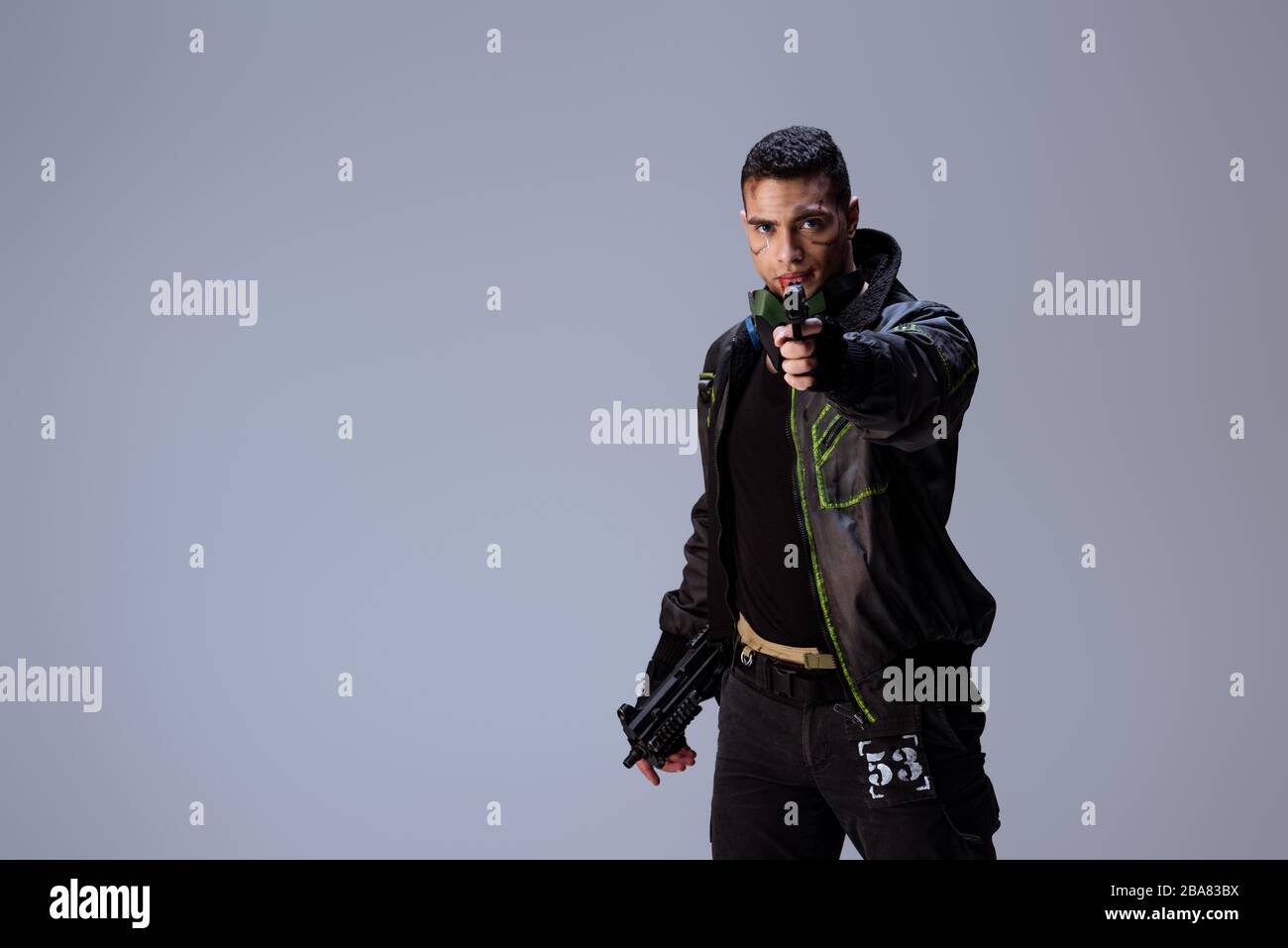 dangerous bi-racial cyberpunk player aiming gun isolated on grey Stock Photo