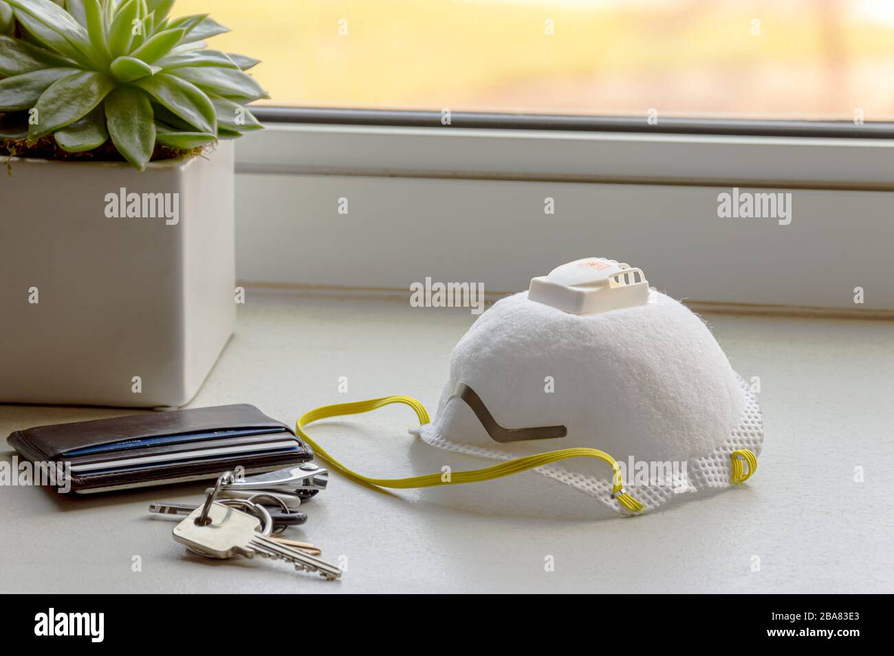 N95 Respirator Mask with keys and wallet on a counter at home. Personal Protective Equipment. Stock Photo