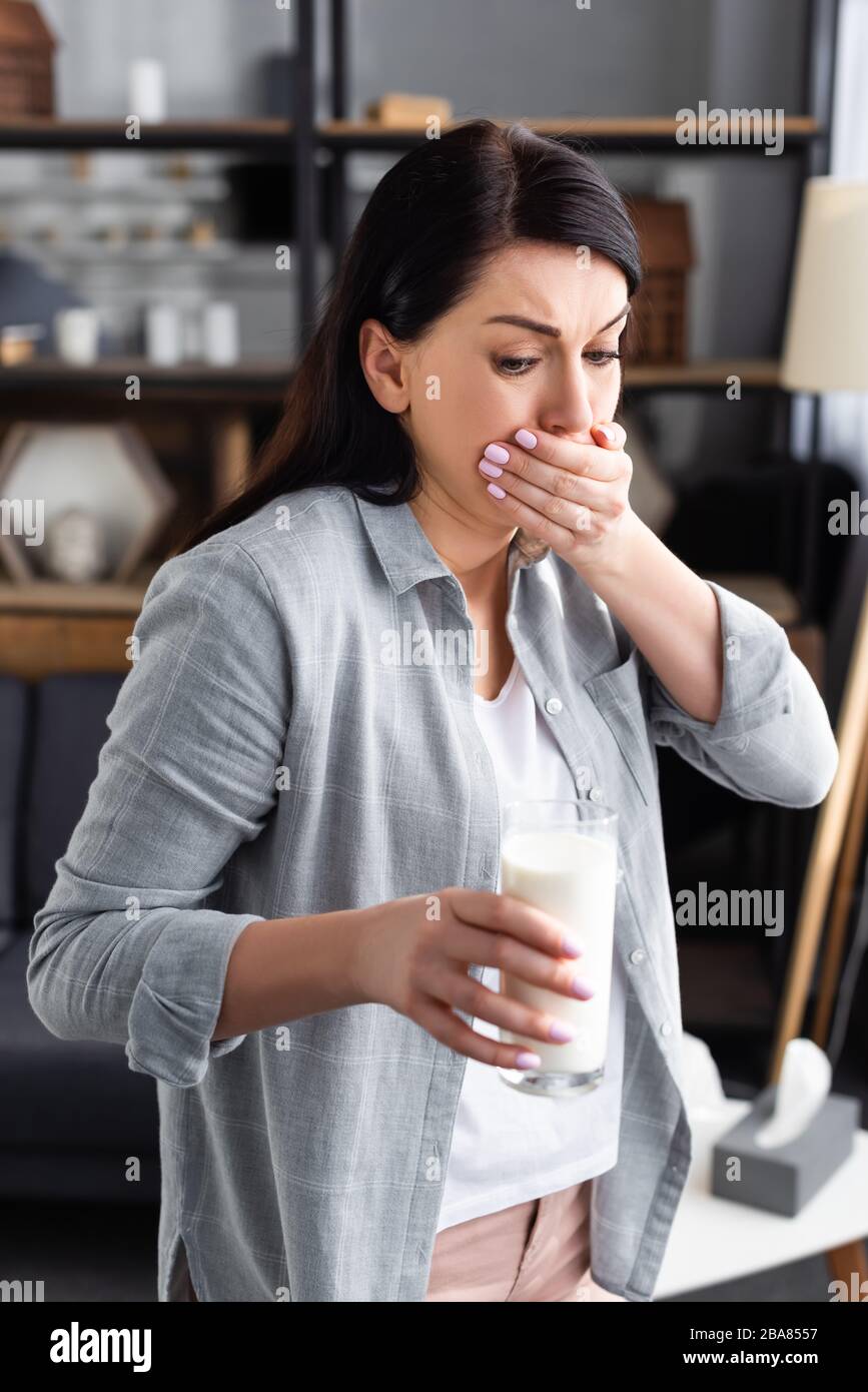 woman with lactose intolerance and nausea looking at glass of milk