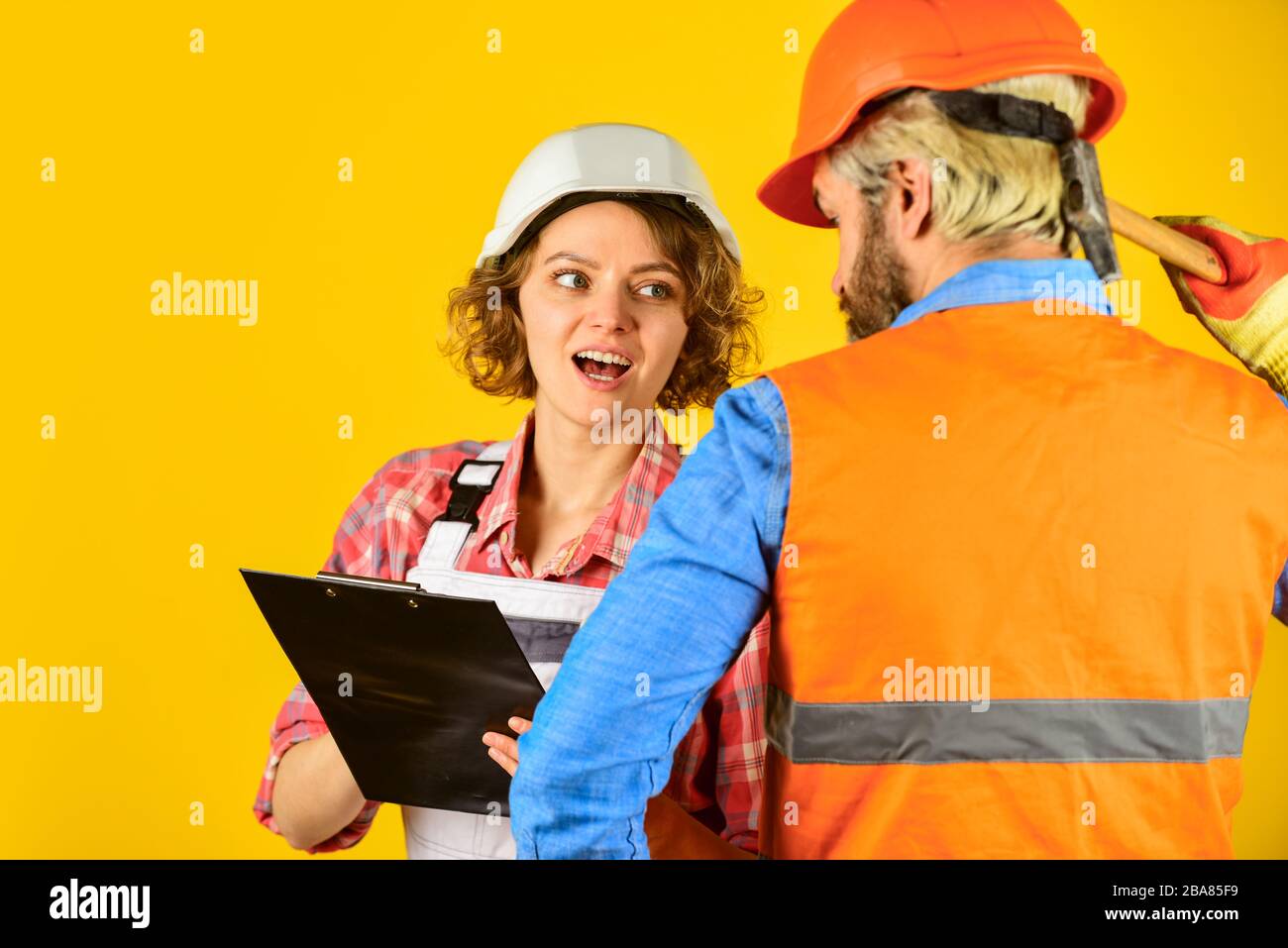 Control process. Renovation concept. Discussing renovation with contractor. Couple planning changes renovation apartment. Woman and man safety hard hat. Redevelopment of home. Couple look documents. Stock Photo