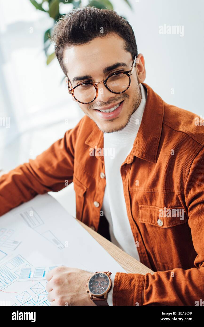 Smiling developer looking away while planning user experience design at table in office Stock Photo