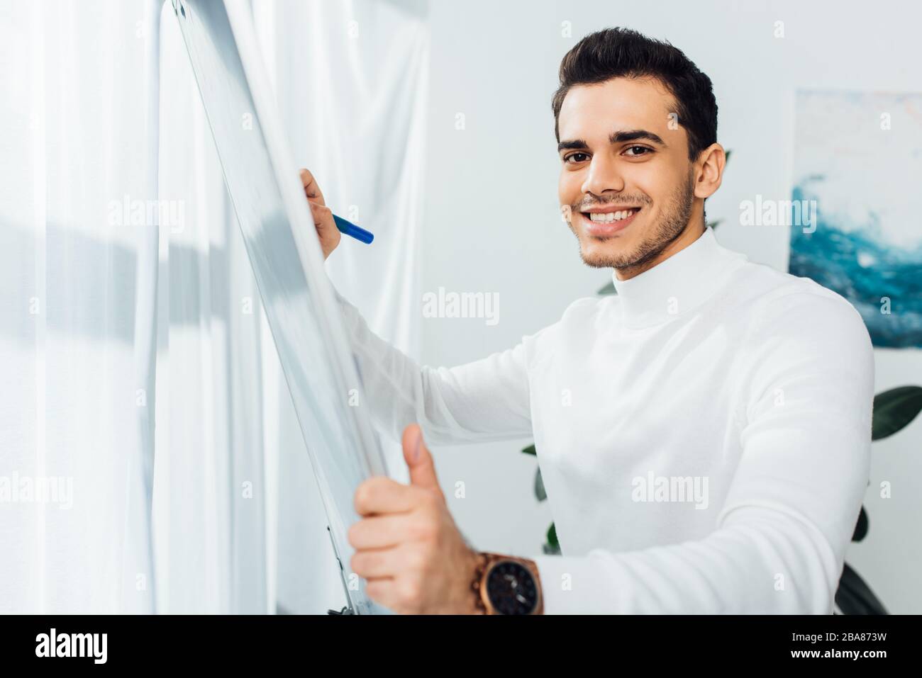 Smiling designer looking at camera while using whiteboard in office Stock Photo