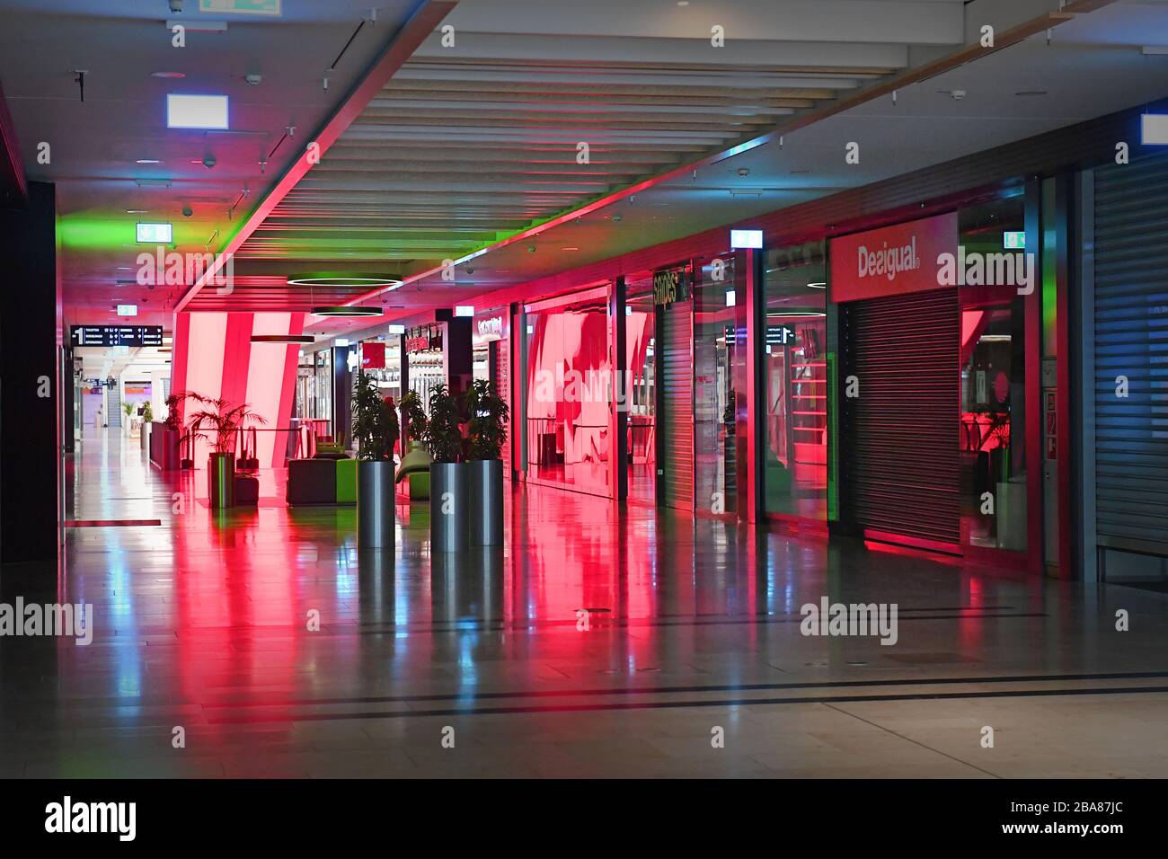 Munich, Deutschland. 26th Mar, 2020. Empty aisles and escalator-closed  shops, shops, shops bathed in red light. Closed shopping mall due to corona  pandemic, shopping center, Riem Arcaden on March 26th, 2020. @Sven