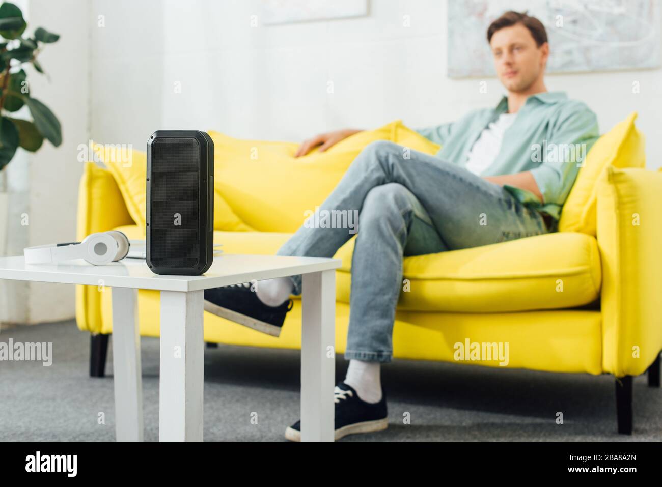 Selective focus of wireless speaker and headphones on coffee table and
