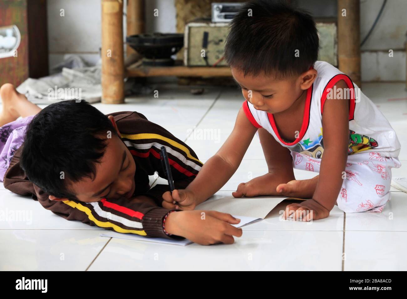 Bali, Indonesia - January 24, 2009: Children of an Indonesian artist paint while sitting on the floor. Bali is famous for talented artists. Bali, Indo Stock Photo