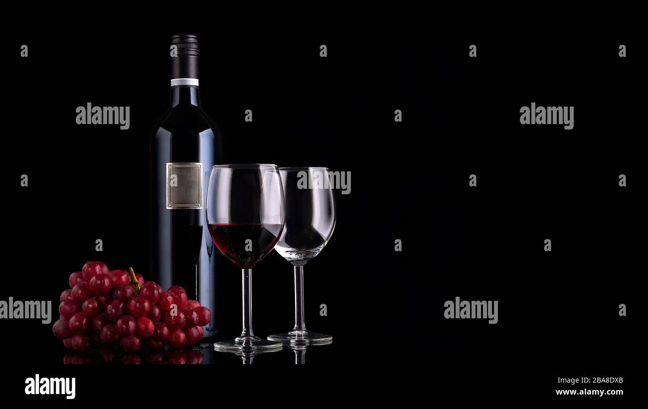 Closed red wine bottle with empty label, small branch of grape and two