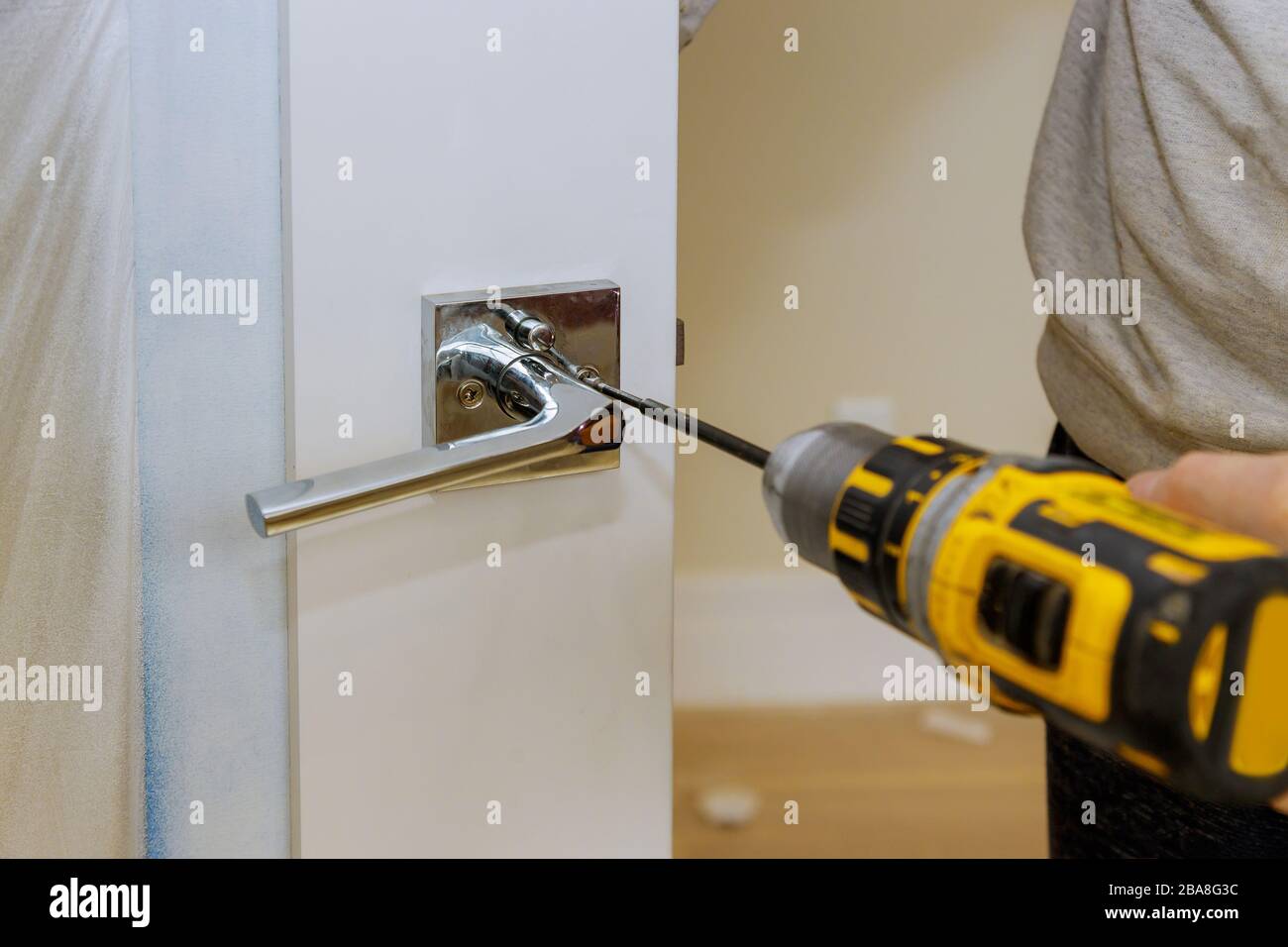 Carpenter installing door lock in the new house with a screwdriver