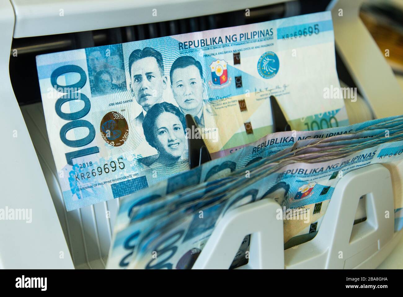 Close up view of a 1000 Philippine peso cash exiting the money counter machine Stock Photo